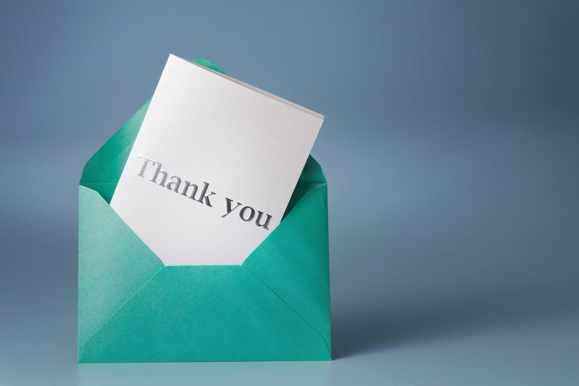 A thank you card in a teal blue envelope. 