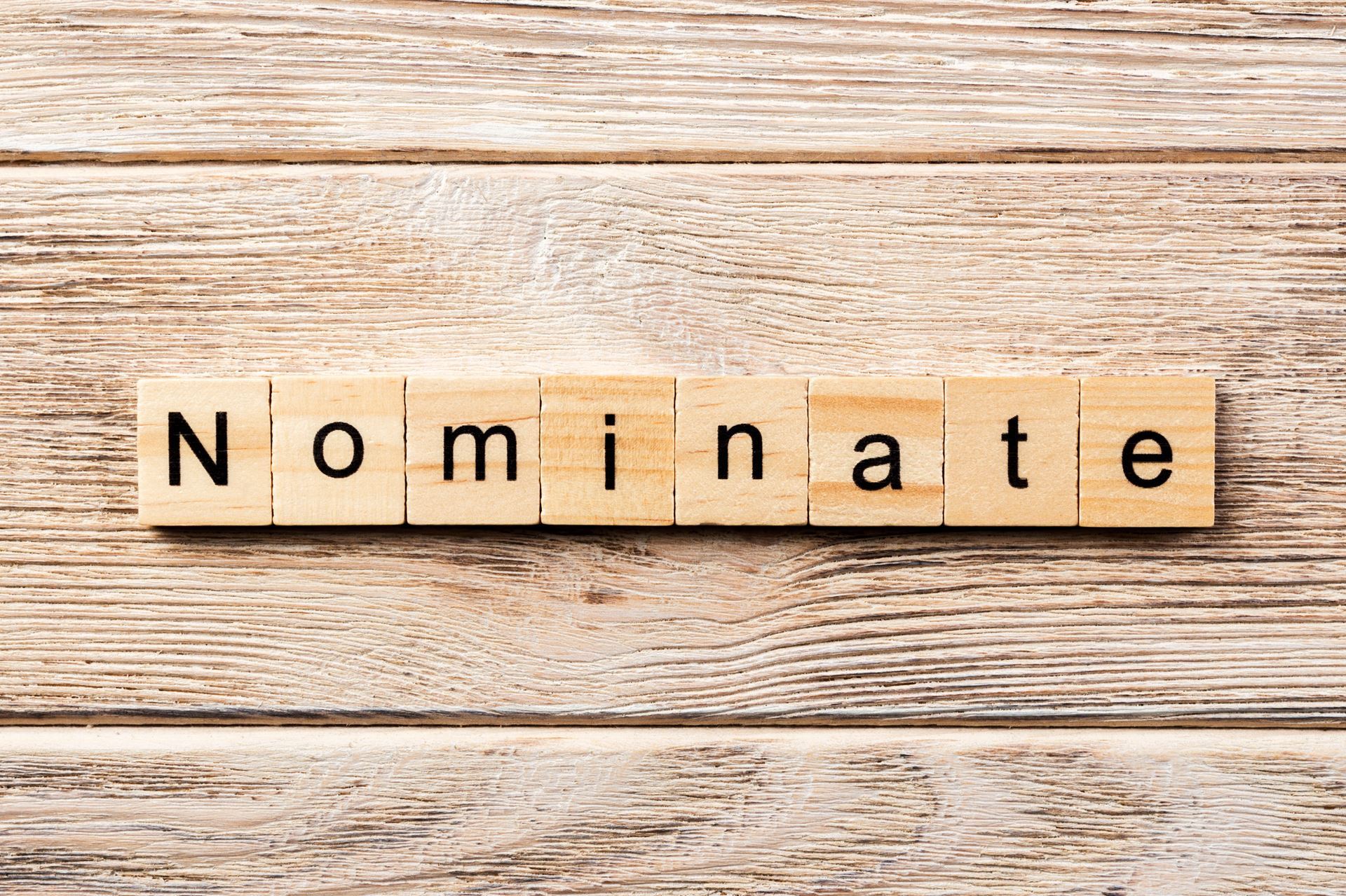 Stock image of scrabble word tiles with the letters to spell nominate. 